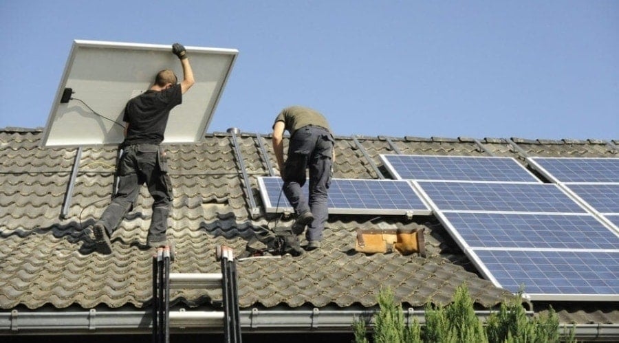 人们在屋顶上安装太阳能电池板