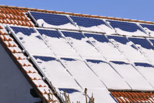 屋顶上的一组太阳能电池板被雪覆盖